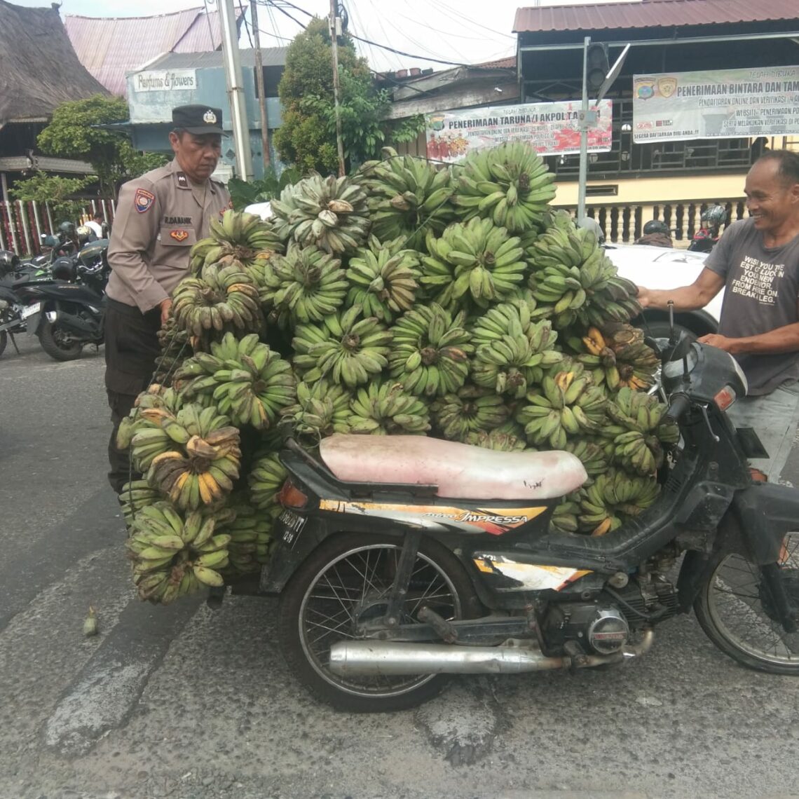 Antisipasi Macet, Bhabinkamtibmas Bantan Bantu Warga Angkat Buah Pisang Jatuh.